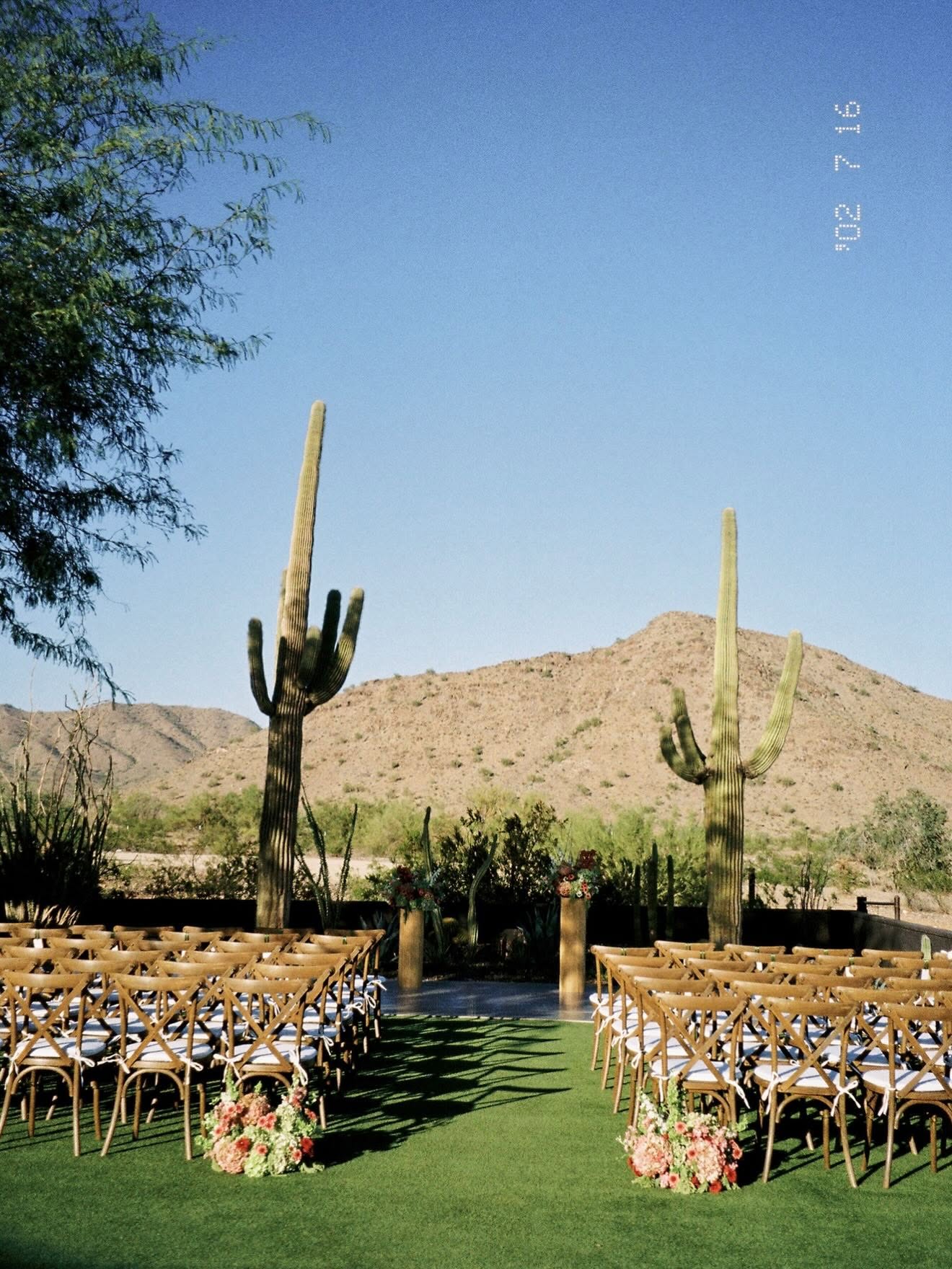 Empty ceremony aisle with floral arrangements at the base of the front-row chairs